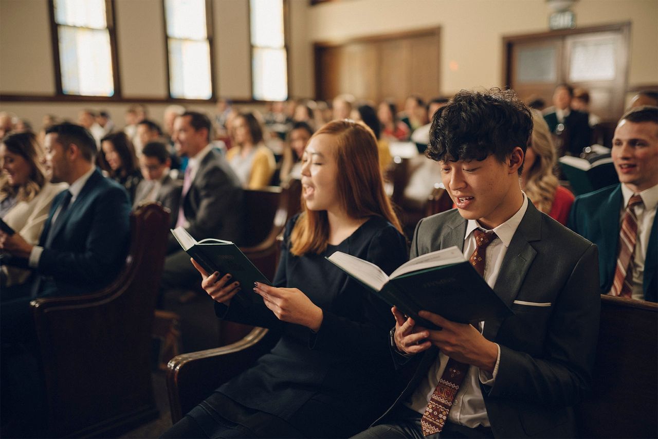 Two woman sitting at church singing hymn